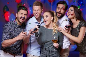 Group of friends singing karaoke at party